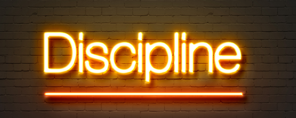 The word discipline styled as yellow lights on a white brick background