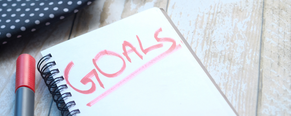 The word goals in red marker on a white notepad