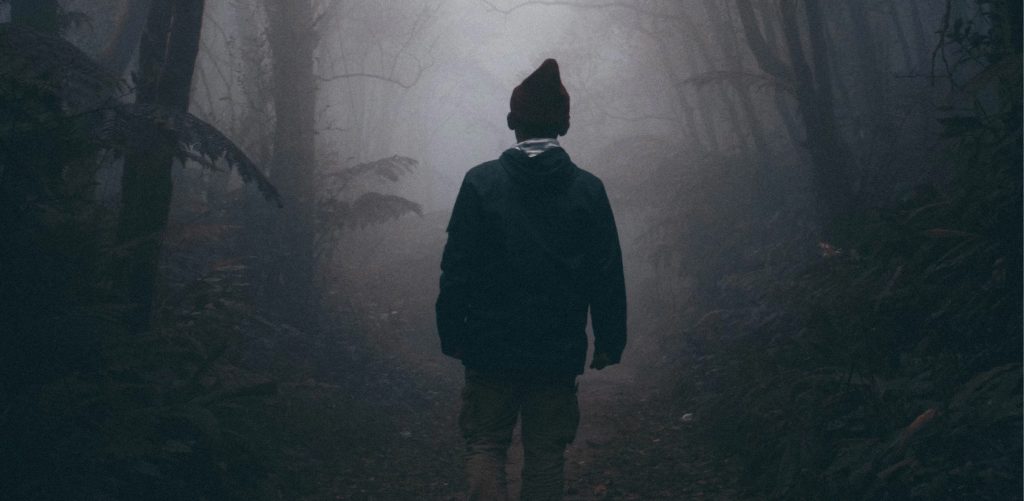 a male silhouette walks into a foggy forest